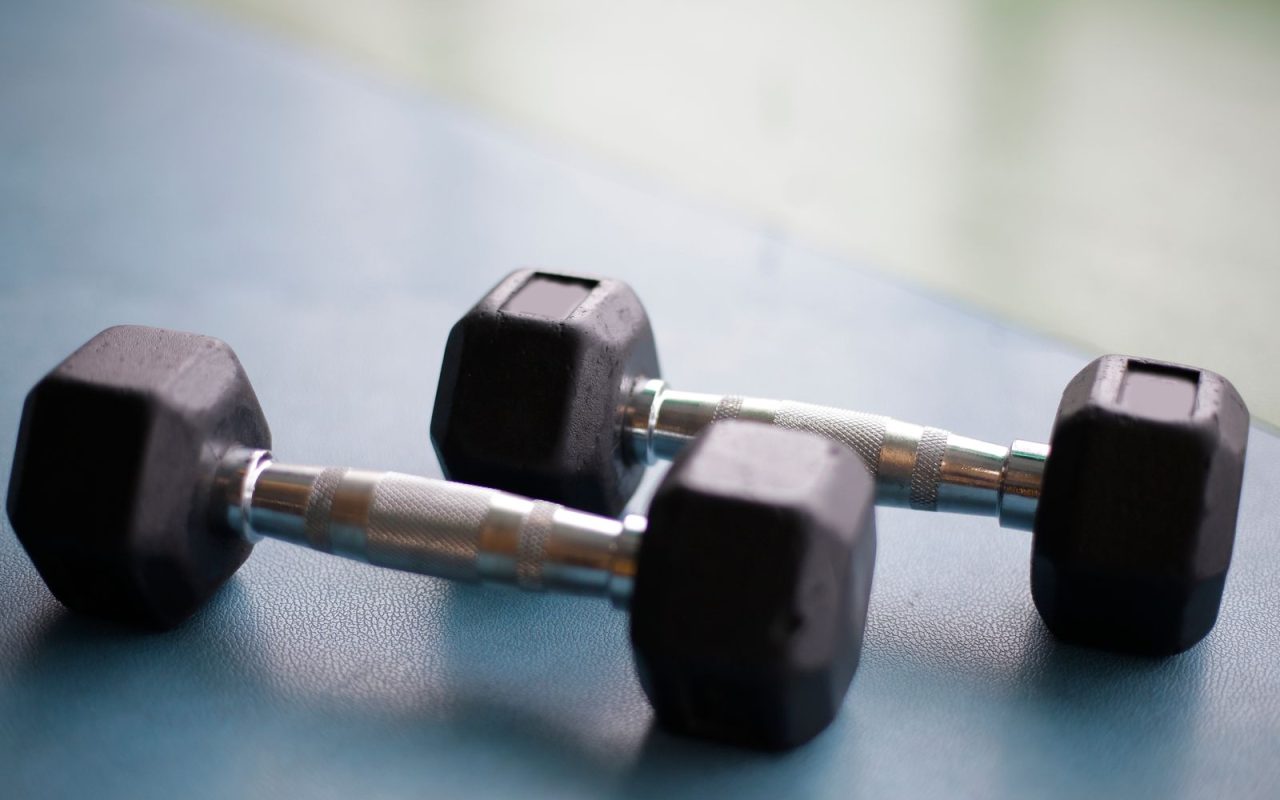 Two black hex dumbbells on a gym floor