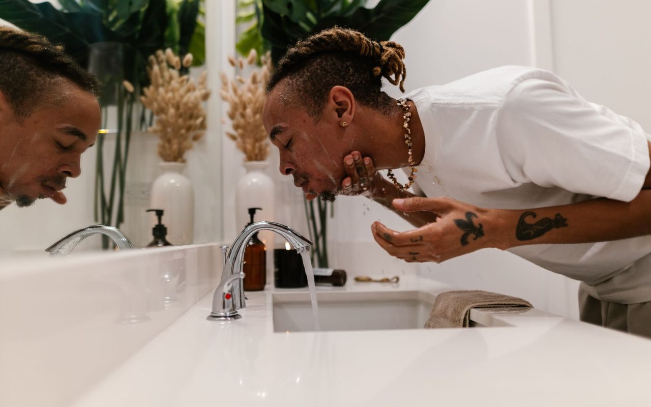 A man washing his face at a bathroom sink