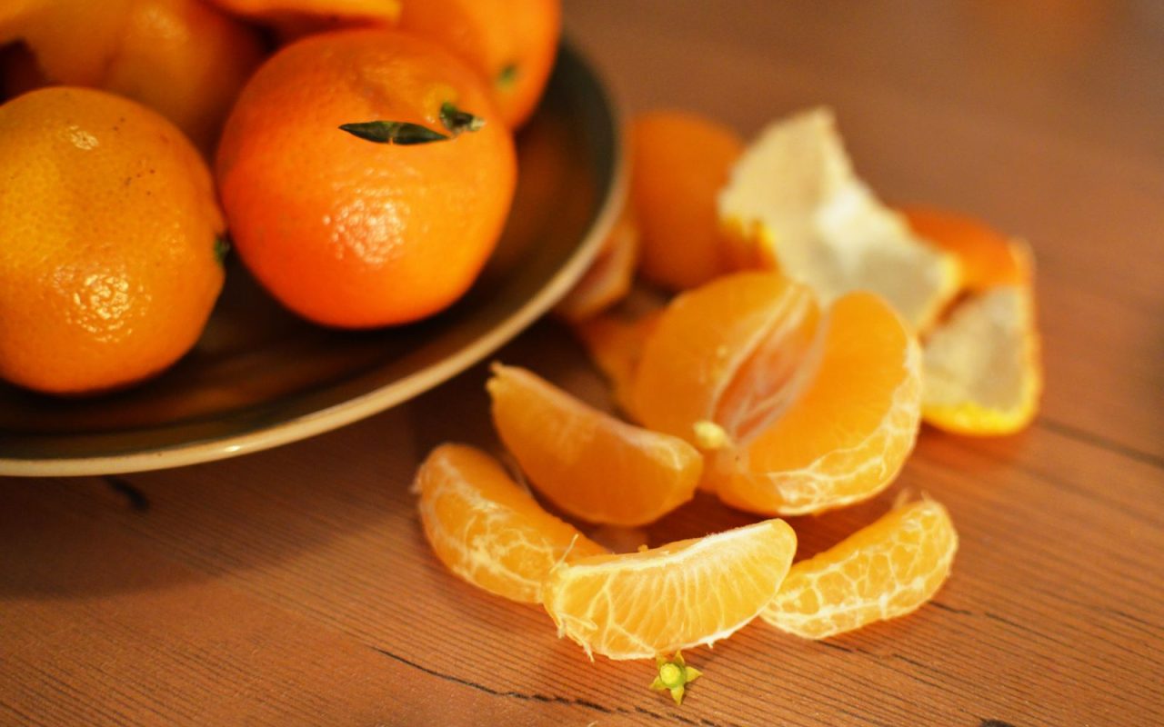 Fresh oranges and peeled tangerines on a wooden table