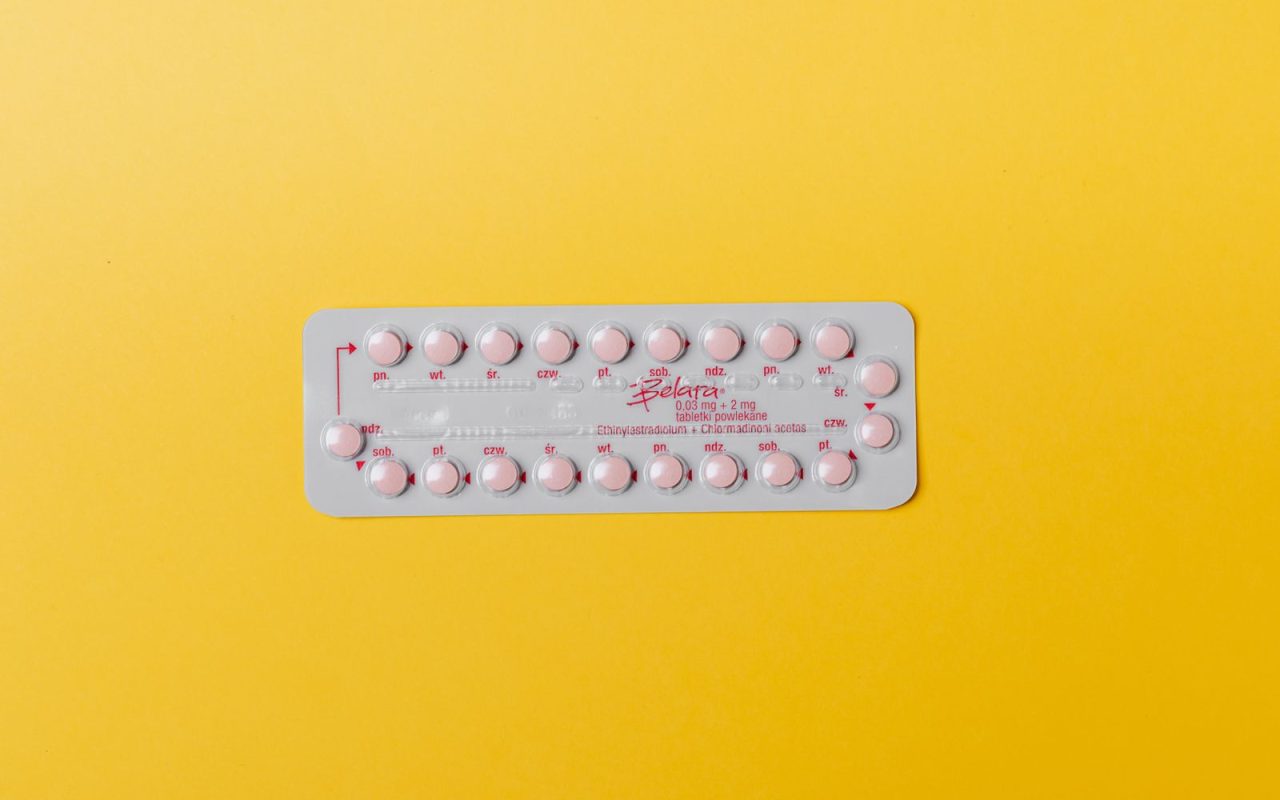 A blister pack of pink pills on a yellow background