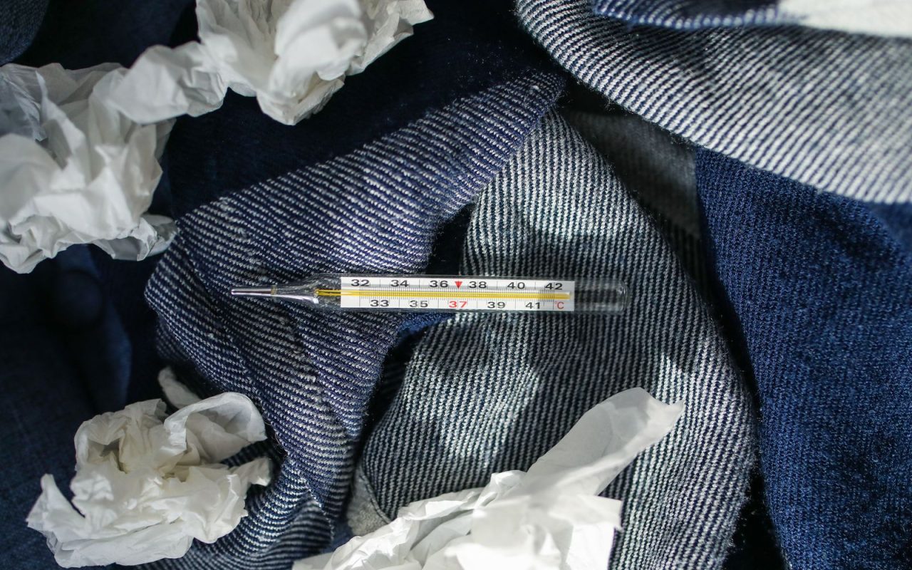 A thermometer and used tissues on a blanket