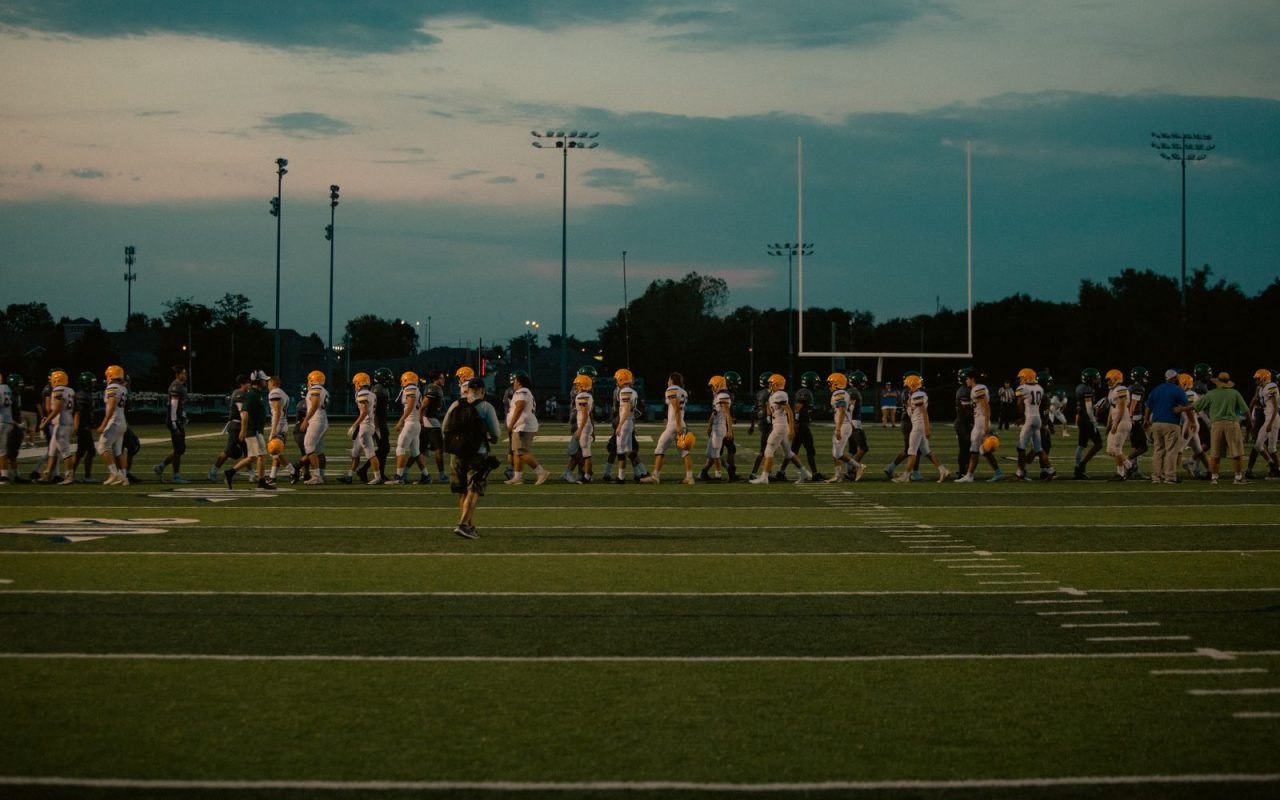 Players walking off an American football field at dusk