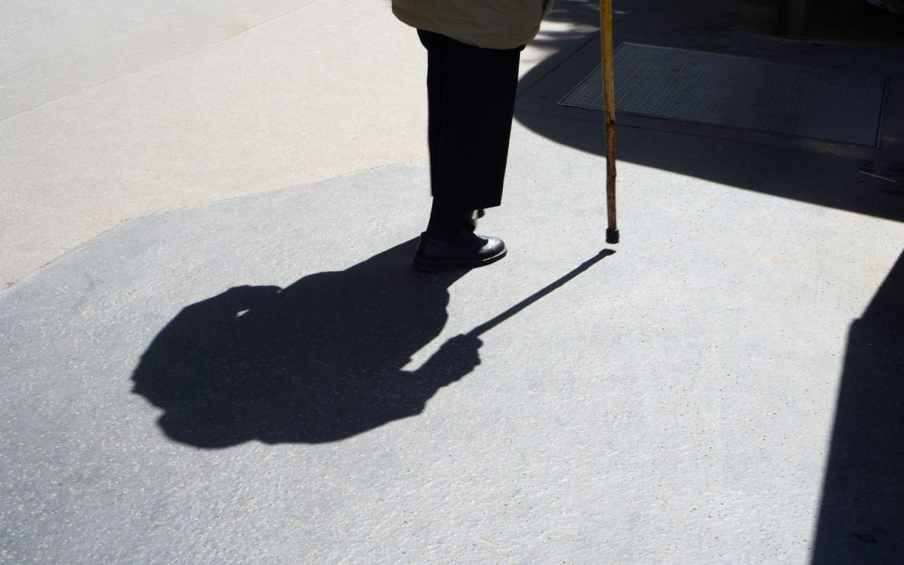 Silhouette of an older person walking with a cane
